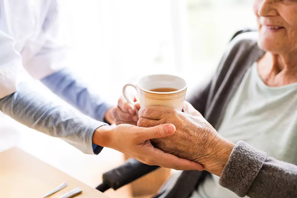 Engagierte Pflegerin reicht einer freundlichen Patientin eine Tasse Tee und leistet Ihr Gesellschaft