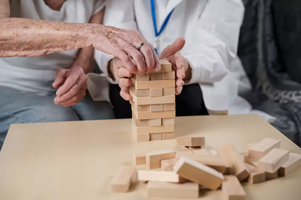 Seniorin spielt ein Spiel und baut einen Turm aus Holzklötzen zum Zweck des Gedächtnis- und Motoriktraining